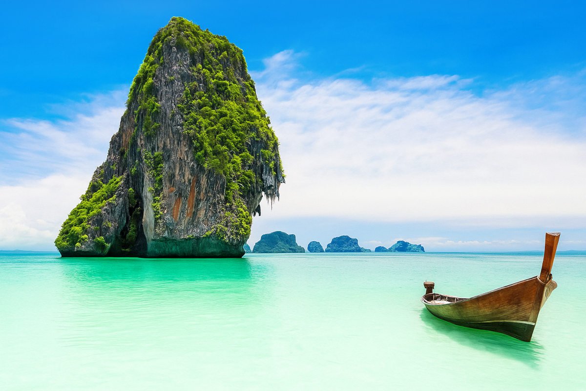 View from a Phuket beach overlooking the turquoise sea with lush tropical hills in the distance.
