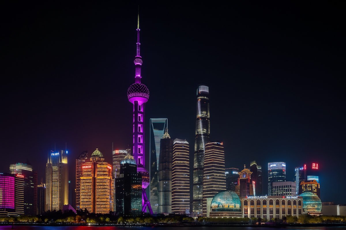 A panoramic view of the Shanghai skyline featuring the Oriental Pearl Tower, modern skyscrapers, and the Huangpu River during nighttime.