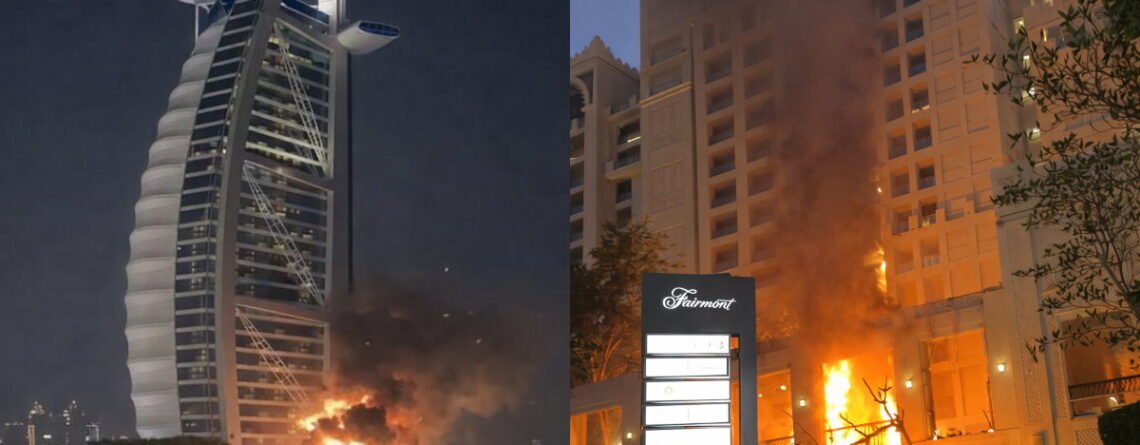 Night-time image showing Fairmont The Palm at Palm Jumeirah and the Burj Al Arab with visible impact damage, smoke and small fires from missile/drone debris.